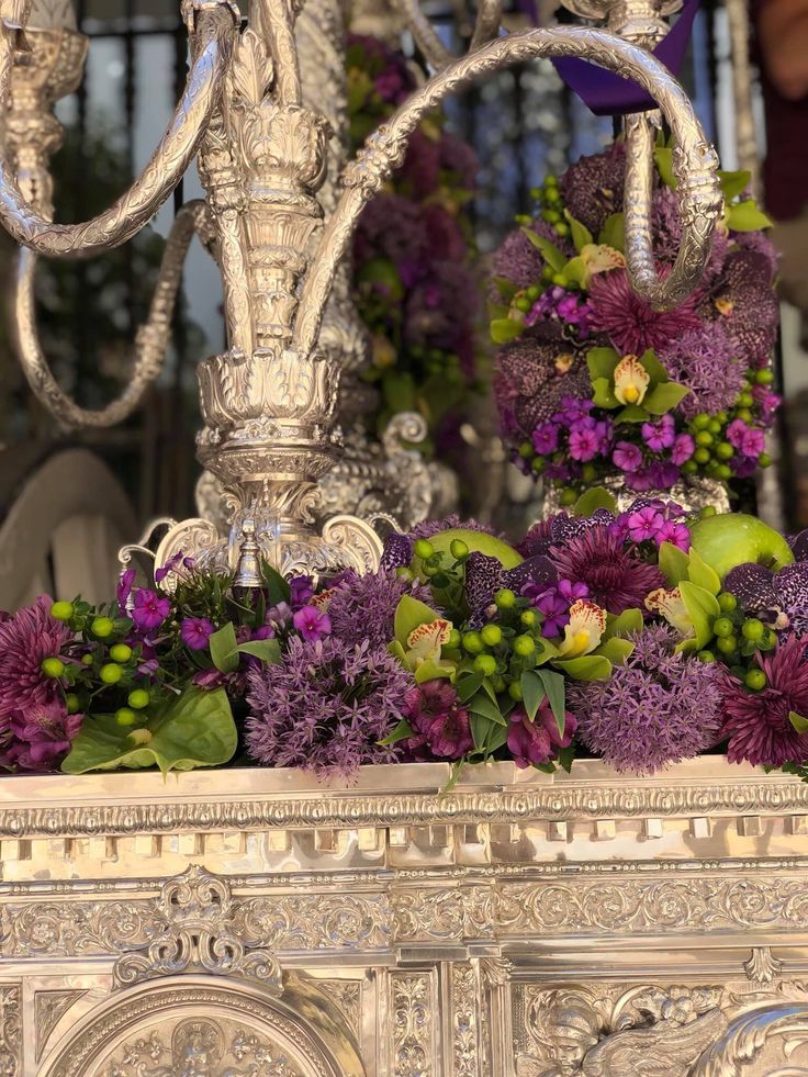 Decoración floral con flores naturales de tonos morados y verdes en un arreglo realizado para un trono de Semana Santa.