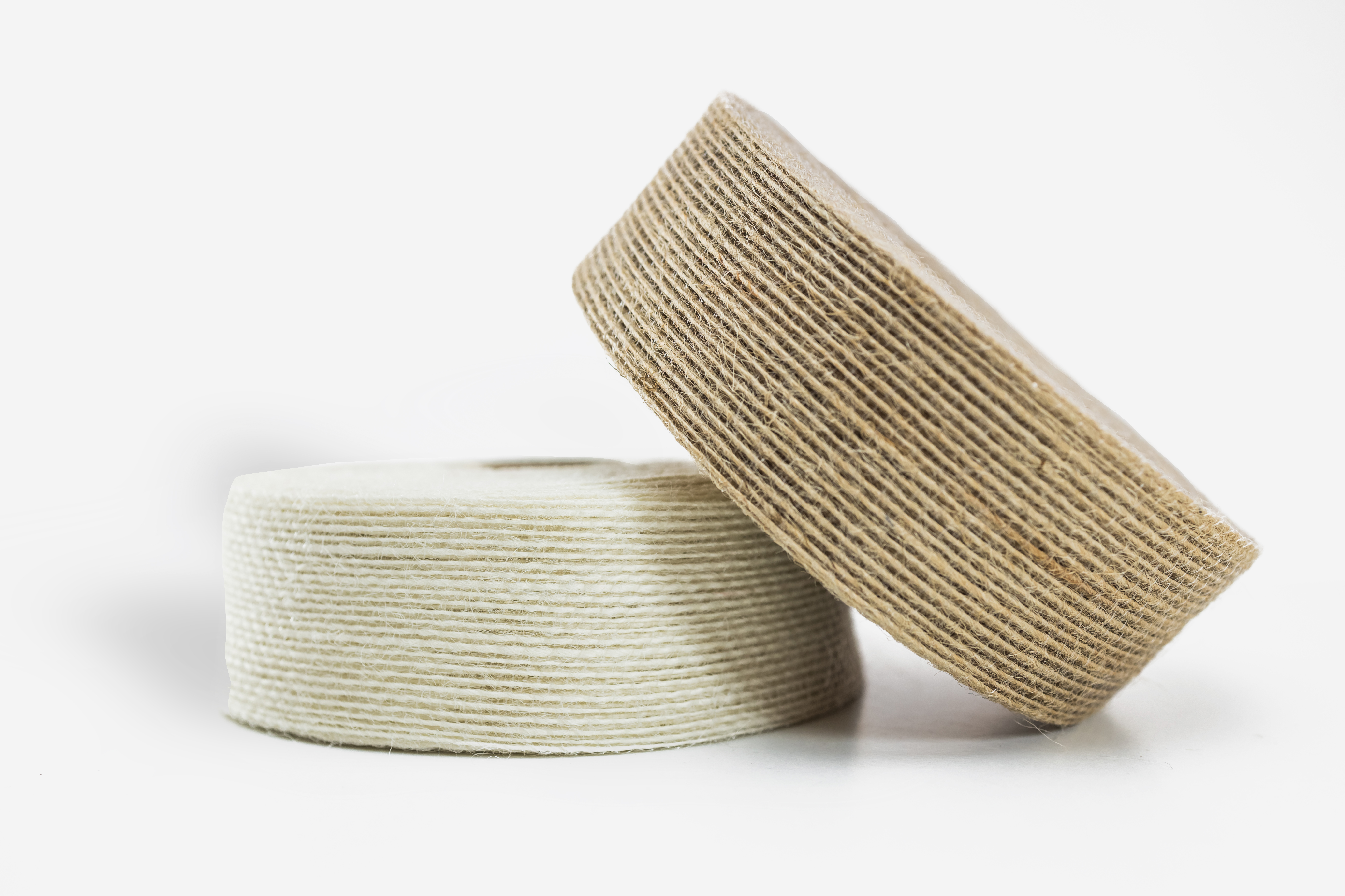 Rollo de cinta de yute natural de trama cerrada y bordes reforzados, con textura rígida y color tierra suave, presentado sobre una superficie neutra para resaltar su acabado artesanal.