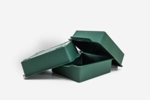 Soporte técnico de rejilla plástica de color verde con media esfera de espuma floral de alta densidad integrada, diseñada para la sujeción estructural de arreglos florales sobre fondo blanco.