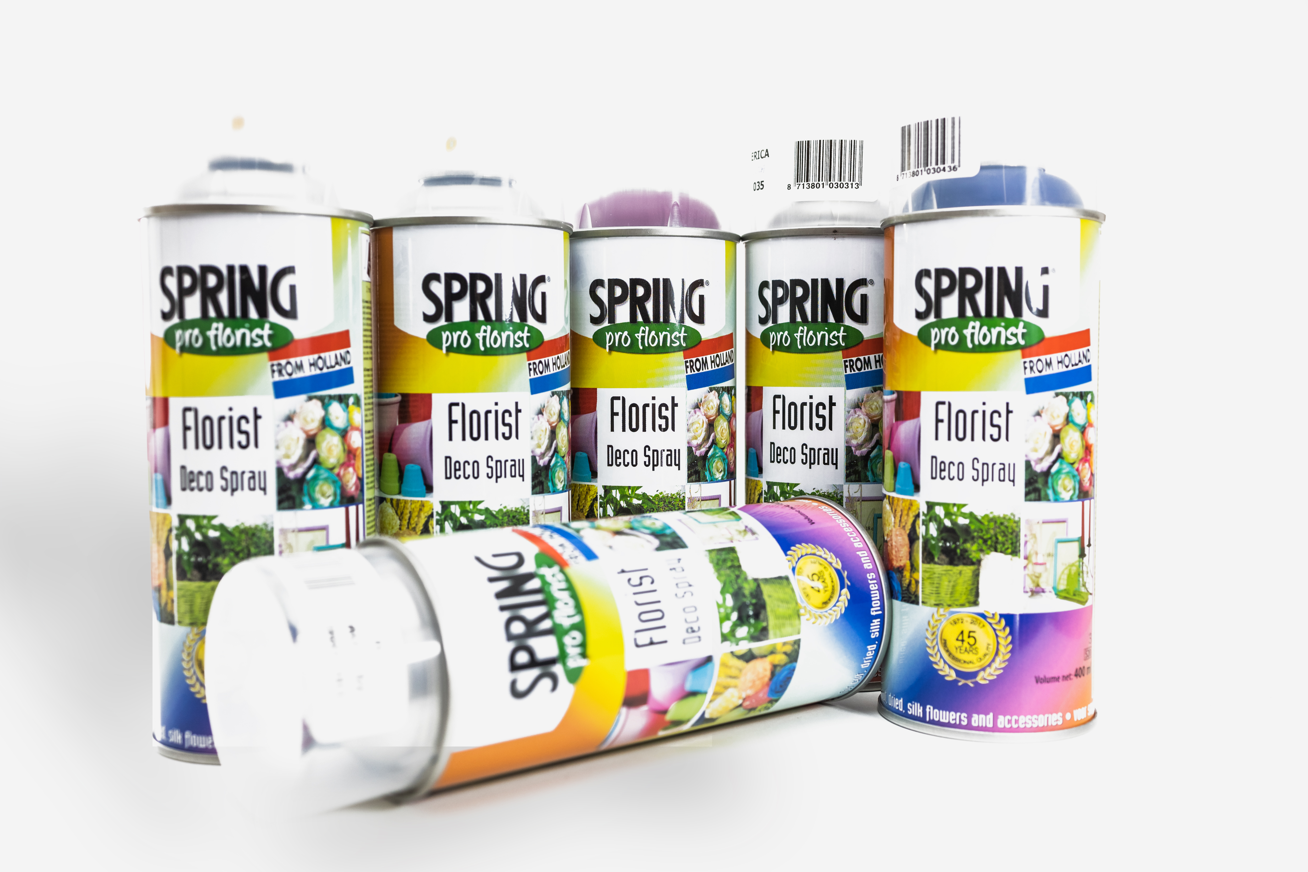 Envase cilíndrico de spray profesional para floristería, con boquilla de difusión fina que libera una bruma transparente sobre un arreglo floral, resaltando el brillo de las hojas sobre un fondo neutro.
