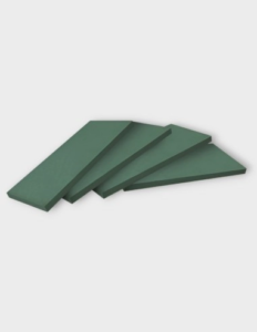 Plancha de esponja floral de alta densidad y forma rectangular, mostrando su textura porosa y su color verde característico, ideal para el montaje de arreglos sobre superficies planas.